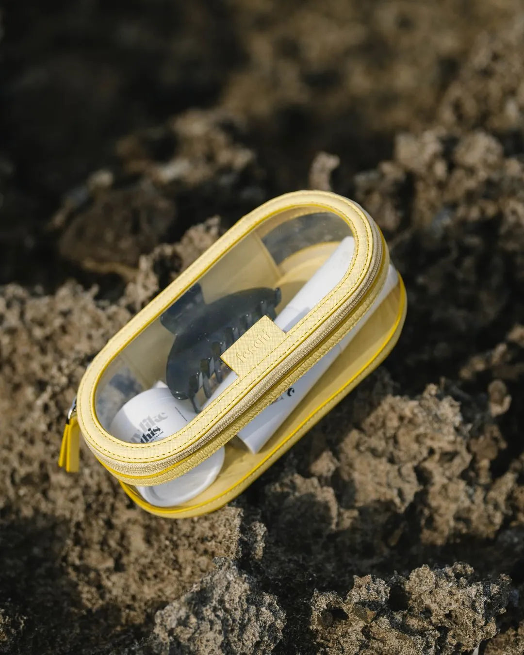 Travel Buddy Juicy Lemon, gefüllt mit Travel-Size-Produkten und einer Spange von feschi