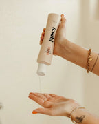 Frau drückt feschi volumen Shampoo in der Dusche in die Hand